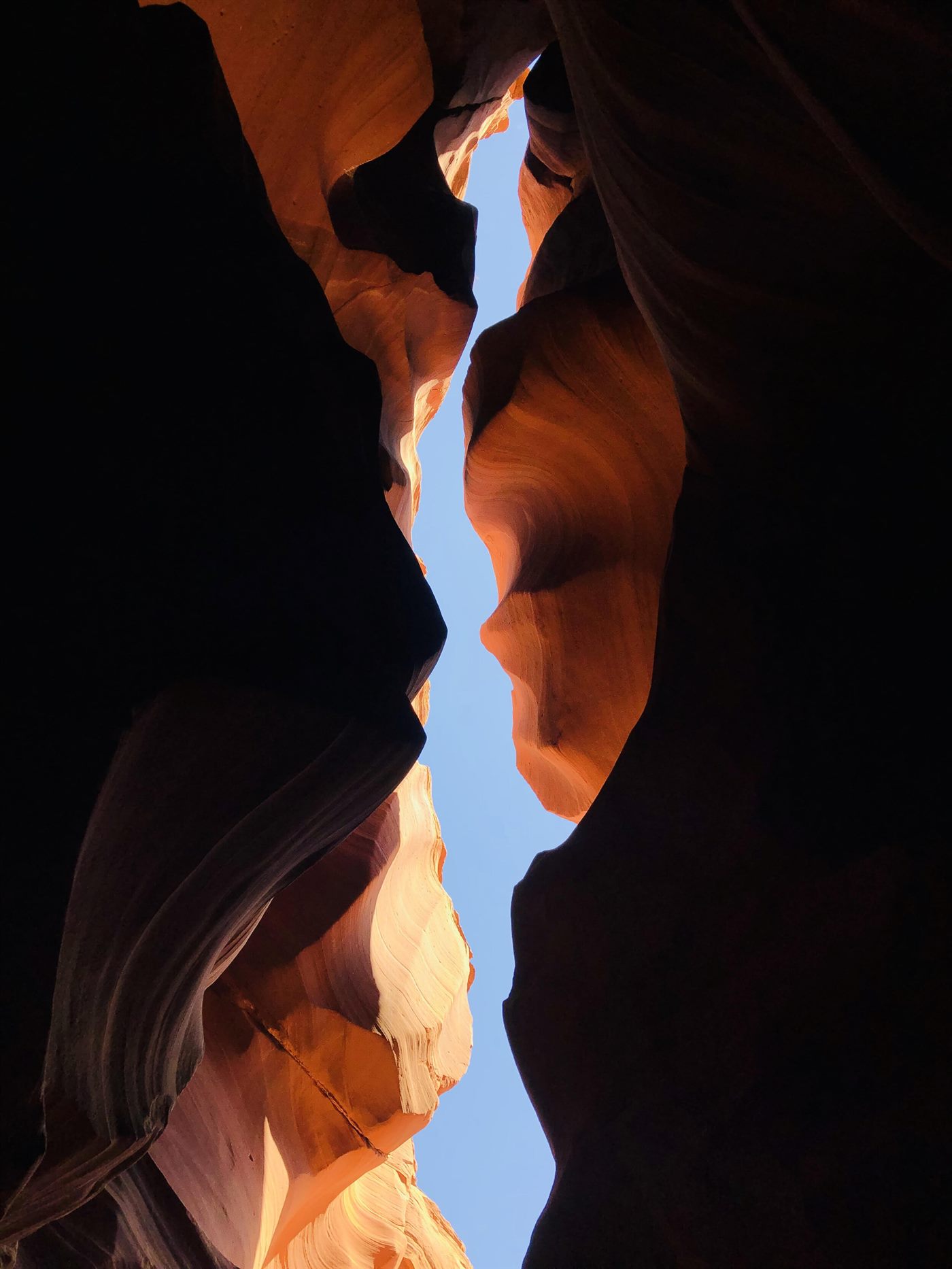 Looking up at a narrow strip of sky from deep inside a slot canyon